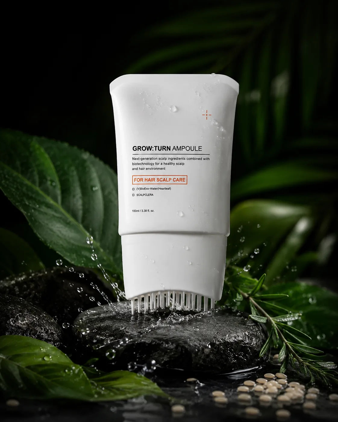 A white squeeze tube of hair scalp care product labeled 'GROW-TURN AMPOULE' stands upright on dark wet stones with water splashing around it, surrounded by green leaves and small beige beads against a dark background.